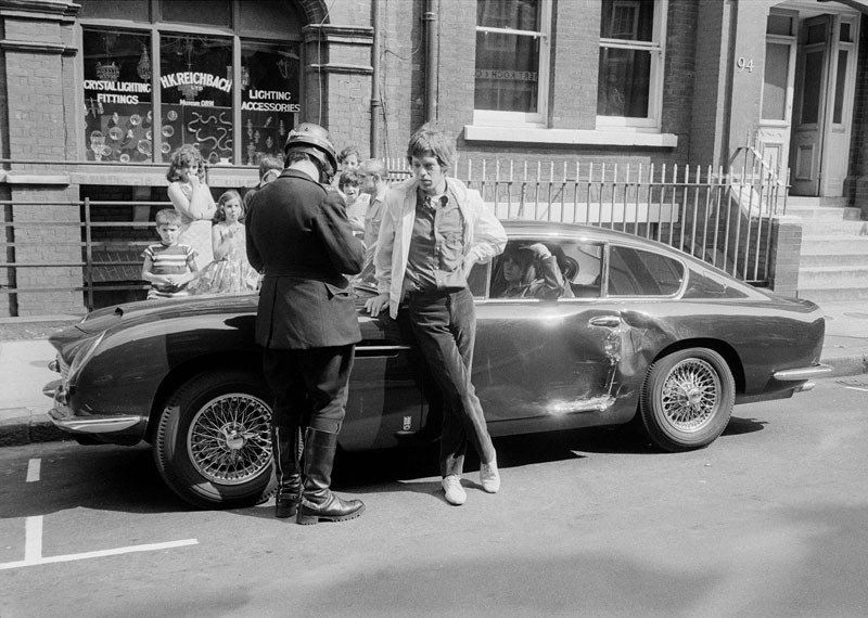 Jagger talks to a policeman beside his damaged DB6 after a collision in central London in 1966